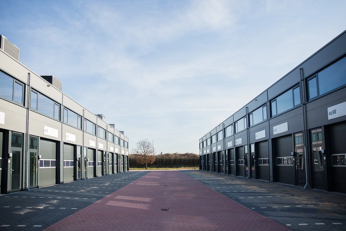 Moderne bedrijfsunits aan de Laan van ’s-Gravenmade met een rode bestrate weg tussen twee gebouwen.